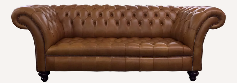 A classic brown leather Chesterfield loveseat sofa with deep button tufting, rolled arms, and nailhead trim, shown against a solid black background.