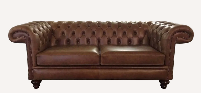 A classic brown leather Chesterfield loveseat sofa with deep button tufting, rolled arms, nailhead trim, and dark wooden legs, shown against a plain white background.