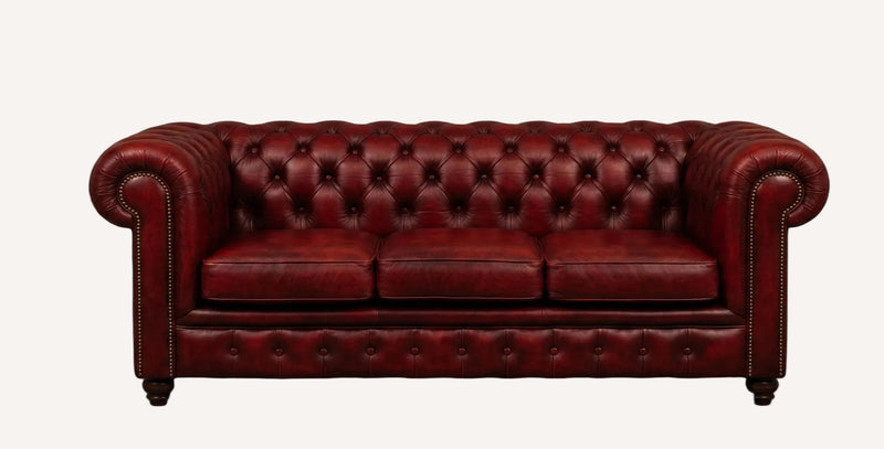 A classic Chesterfield loveseat sofa upholstered in deep burgundy red leather, featuring deep button tufting, rolled arms, and nailhead trim, shown against a solid black background.